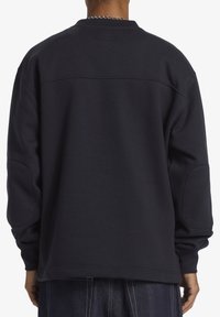 Sudadera de gran tamaño en color azul marino con cuello redondo, hombros caídos y tejido texturizado con un acabado suave. Detalles de costura sutiles en la parte trasera.