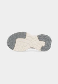 Semelle d'une chaussure de sport en caoutchouc blanc et gris, présentant des motifs de traction texturés pour l'adhérence et la durabilité.