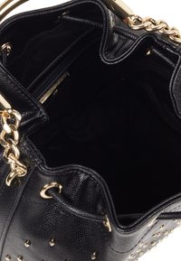 Musta nahkalaukku, jossa on kultasävytteiset yksityiskohdat. Ulkopuolella on niittejä, avoin yläpään avaus ja pehmeä kangaspäällysteinen sisustus, jossa on vetoketjullinen tasku.