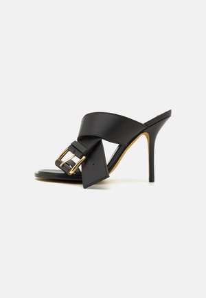 Black high-heeled mules with a smooth leather upper, featuring a wide strap and a gold-tone buckle detail on the front.