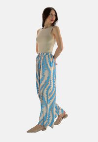 Beige t-shirt med åtsittande passform som matchas med lösa, ljusa mönstrade byxor i blått och beige. Byxorna har resårmidja och avsmalnande fållar.