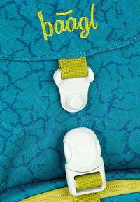 Rucksack aus türkisfarbenem Stoff mit einem strukturierten Muster. Verfügt über gelbe Akzente, einen magnetischen Verschluss und den aufgestickten Markennamen in Gelb.