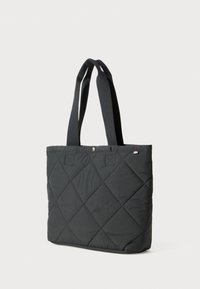 Svart quiltet totebag med diamantstikking, doble brede stoffhåndtak, og en liten logomerke nær toppen.