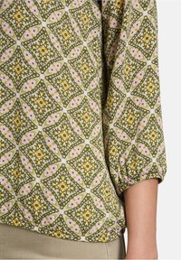 Bluzka w zielono-różowy wzór z motywem diamentów, posiadająca ściągane rękawy i miękką fakturę materiału.