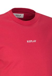 T-shirt in cotone rosso con scollatura a girocollo. La parte anteriore presenta il marchio "REPLAY" ricamato in bianco. Texture morbida e liscia.