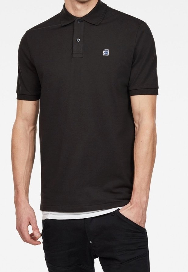 Musta pokeripaita, jossa on kaulus, kaksipainikeinen napitus ja pieni logo vasemmassa rinnassa; valmistettu sileästä, pehmeästä kankaasta.