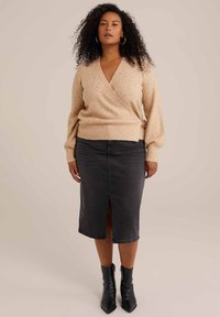 Bežna ovita pulover s teksturiranim zaključkom, v kombinaciji z črno denim svilenko z razporkom spredaj in usnjenimi črnimi čevlji na peto.