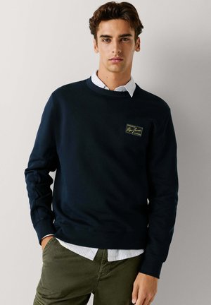 Marineblaue Sweatshirt aus Baumwollmischung, mit gerippten Bündchen und Saum sowie einem kleinen rechteckigen Logo-Patch auf der Brust.