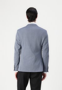 Light blue blazer, structured design, notch lapels, single vent, textured fabric, buttoned details at cuffs, paired with black trousers.
