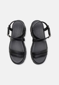 Black sandals with two horizontal straps and a back ankle strap, featuring a textured sole and the brand name "ONLY" embossed on the footbed.