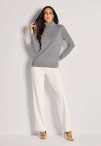 Grau rollkragenpullover mit langen Ärmeln, kombiniert mit hochgeschnittenen weißen Hosen mit vertikalen Nähten und nude-farbenen Absätzen.