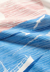 Tejido de algodón con un diseño ondulado en rojo y azul, con acentos blancos que representan aves y el contorno de un barco, superficie texturizada.