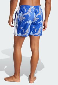 Pantaloni da bagno blu con motivi astratti in azzurro chiaro e bianco, vita elastica e tre strisce laterali bianche, che offrono un design aderente.