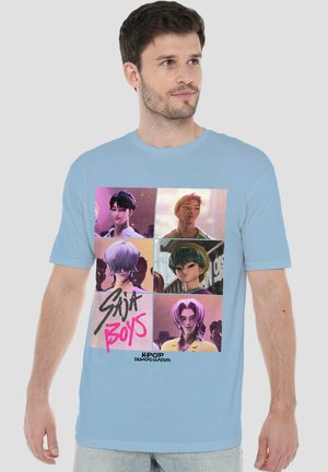 Mann trägt ein hellblaues T-Shirt mit sechs illustrierten Charakteren in bunten Panels, beschriftet mit "Saija Boys" und "Kpop Demon Hunters".
