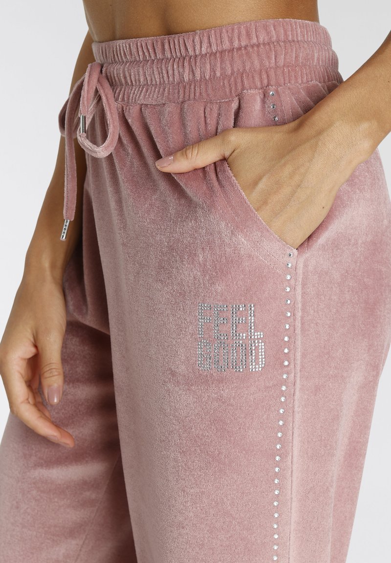 Stofzuigerroze fluwelen joggers met een elastische tailleband en trekkoord. Voorzien van schitterende strass-steentjes en een zijvak voor gemak.
