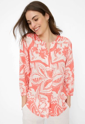 Lyserød bluse med blomsterprint og knaplukning foran, der har trekvartlange ærmer og en afslappet pasform. Fremstillet af et letvægtsstof.