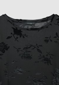 Robe noire à motifs floraux, en tissu doux et texturé avec un léger éclat, décolleté rond, et étiquette indiquant "CALLIOPE S."