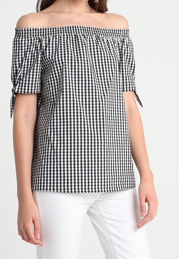 Black and white gingham off-the-shoulder blouse with short sleeves, gathered neckline, and tie accents, paired with white pants.