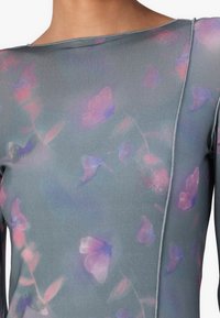 Long-sleeve top in lightweight, stretchy fabric, featuring a gray base with watercolor-style floral patterns in pink and purple. Seam detail on shoulder.