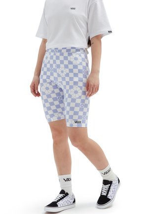 Vaaleansinisiä ruudullisia pyöräilyshortseja, joissa on valkoisia kukkia ja musta Vans-logo. Yhdistetty valkoisten varrettomien sukkien ja mustien Vans-kengien kanssa, joissa on ruudullinen kuvio.