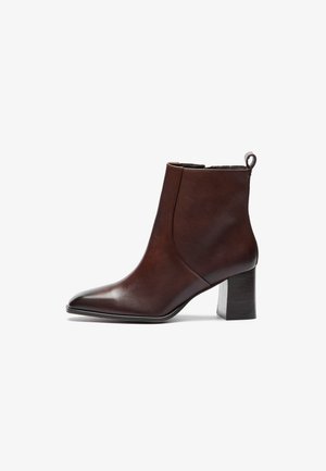 Stivale alla caviglia in pelle marrone con punta affusolata e tacco a blocco. Caratterizzato da un design senza cuciture e da un anello sul retro per una facile vestibilità.