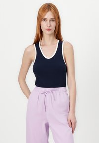 Navy ribbed tank top with a white scoop neckline, paired with light purple drawstring pants, showcasing a relaxed fit and soft texture.
