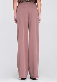Spodnie o szerokich nogawkach wykonane z miękkiego materiału w kolorze pastelowego fioletu, charakteryzujące się gładką fakturą, bocznymi kieszeniami oraz dwoma tylnymi kieszeniami z delikatnym przeszyciem.