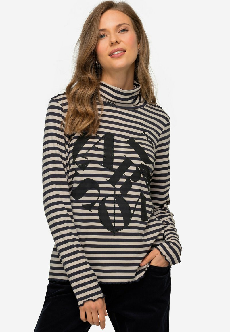 Gestreiftes Langarmoberteil in Beige und Marineblau mit einem hohen Kragen. Mit großen schwarzen Buchstaben auf der Vorderseite bedruckt. Weicher Stoff und gewellter Saum.