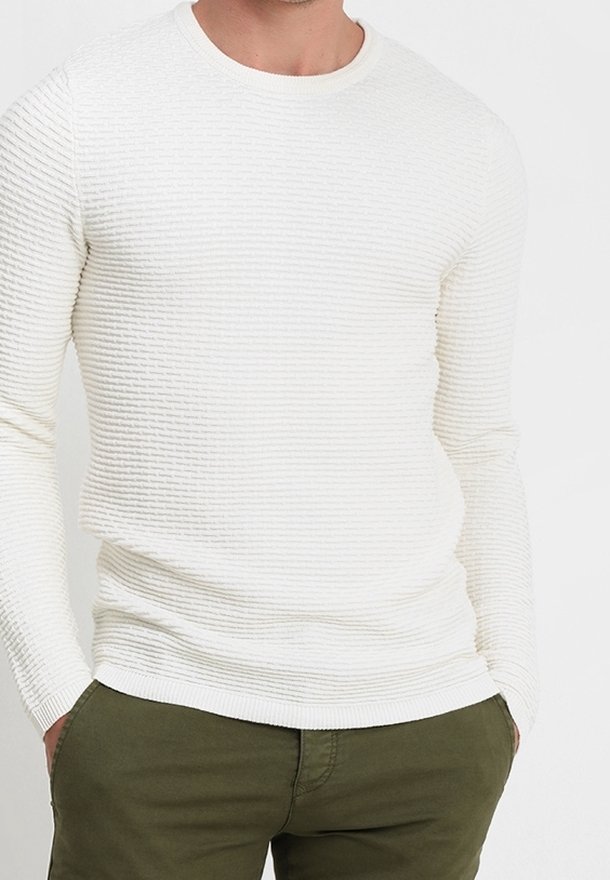 White long-sleeve sweater with a ribbed texture and round neckline, paired with green pants, featuring a slim fit design.