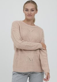 Maglione lavorato a maglia rosa chiaro con un motivo testurizzato, colletto rotondo e polsini a coste, con un distintivo dettaglio a traforo in tutto il capo.