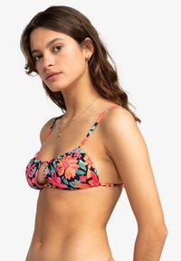 Bloemige bikini-top met een zwarte achtergrond, roze en oranje bloemen, gerimpelde randen en dunne verstelbare banden. Sleutelgatdetail aan de voorkant.