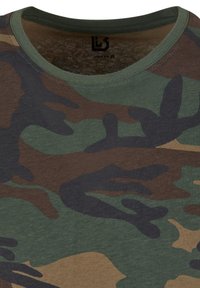 Zöld, barna és fekete árnyalatú terepmintás póló; rövid ujjú, kerek nyakú, pamut anyagból, puha tapintású.