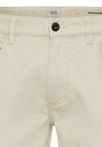Beige Baumwollhose mit Reißverschluss und Knopfverschluss, ausgestattet mit einer einzelnen Vordertasche und dezenter Textur im Stoff.