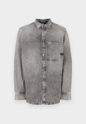 Camisa de mezclilla gris, de botones, de manga larga, con tejido de peso medio, un bolsillo en el pecho, acabado desgastado con botones en contraste, cuello clásico.