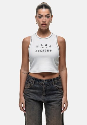 Witte cropped tanktop met zwarte grafische tekst, gecombineerd met hoge zwarte denim jeans met een vervaagde textuur en klassieke zakken.