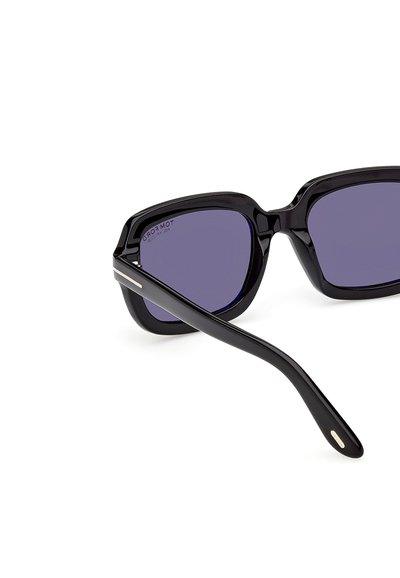 Lunettes de soleil rectangulaires noires avec des verres violet foncé et un mince accent argenté sur la branche, inclinées sur un fond blanc.