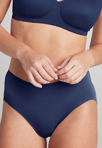 Set di lingerie blu navy realizzato in tessuto morbido, con reggiseno leggermente imbottito e slip a vita alta con elastico elastico.