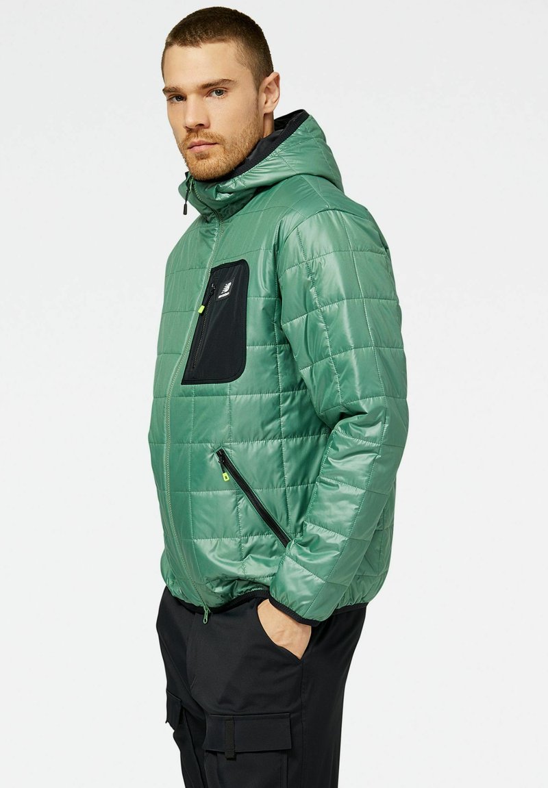Grüne Daunenjacke mit Kapuze, ausgestattet mit einer schwarzen Brusttasche und seitlichen Reißverschlusstaschen. Strukturiertes, gesteppte Design mit kontrastierenden Details.
