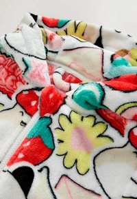 Veste à capuche en polaire avec un motif coloré de fraises, de fleurs et de formes abstraites en rouge, jaune, vert et rose sur un fond blanc.