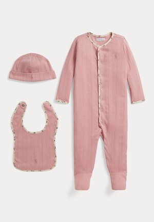 Bonnet bébé côtelé rose, bavoir et grenouillère à pieds avec bordure florale, disposés à plat sur fond blanc.