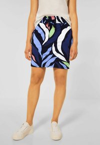 En marinblå kjol med ett lövmönster i grönt, vitt och ljusblått, med elastisk midja och dragsko. Bärs med vita sneakers.