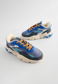 Niebieskie i szare sneakersy z siateczkową i syntetyczną cholewką, z teksturowanymi akcentami, pomarańczowymi sznurówkami i masywną, kremową podeszwą.