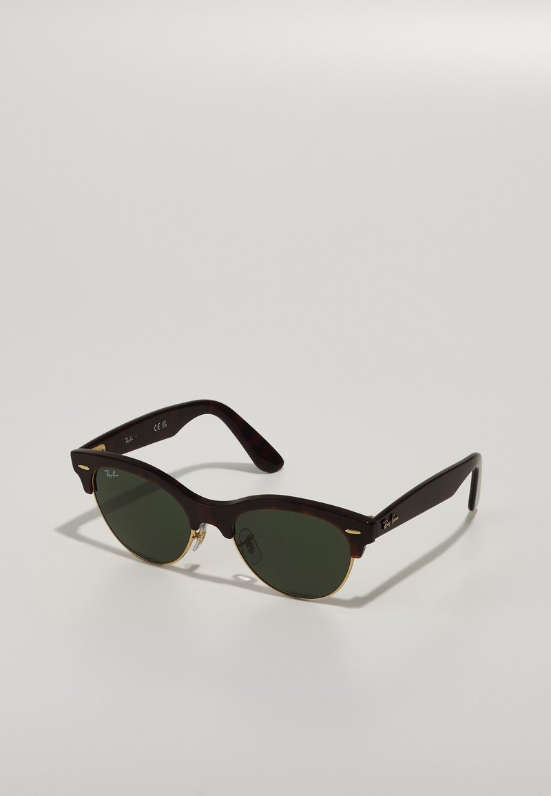 Aurinkolasit kameeleonsa, joissa on vihreät linssit, vintage-muotoilu, ohuet kultaiset yksityiskohdat ja tyylikäs kehysdesign.