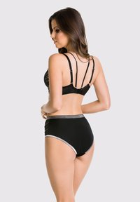 Czarny zestaw bielizny składający się z koronkowego biustonosza z wieloma paskami oraz majtek typu high waist z srebrnymi akcentami i detalami.