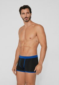 Boxer shorts negros con acentos y cinturilla azul, hechos de una tela elástica, con forma ajustada, que presentan un diseño sencillo y sin patrones.