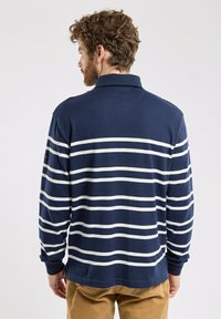 Polo à manches longues bleu marine avec des rayures blanches horizontales, une texture douce et un col classique. Dos uni avec une coupe décontractée.