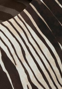 Bruin en crèmekleurige stof met verticale golvende strepen. De textuur lijkt glad te zijn, met lichte variaties in de schaduw van de strepen.