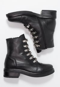 Czarne skórzane botki za kostkę z zaokrąglonym noskiem, srebrnym okuciem i niskim, blokowym obcasem. Zamek błyskawiczny po boku i przeszycia.