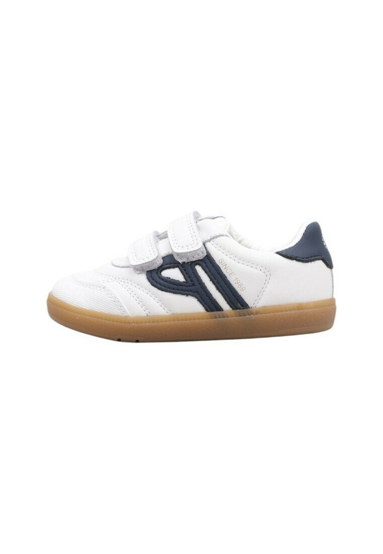 Zapatilla deportiva blanca con acentos en azul marino, correas de velcro y suela de goma. Presenta líneas cosidas y un logotipo en relieve en el lateral.