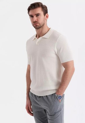 Polo a maniche corte in cotone misto color crema chiaro, con colletto, superficie testurizzata e polsini a coste, abbinato a pantaloni grigi a righe sottili.